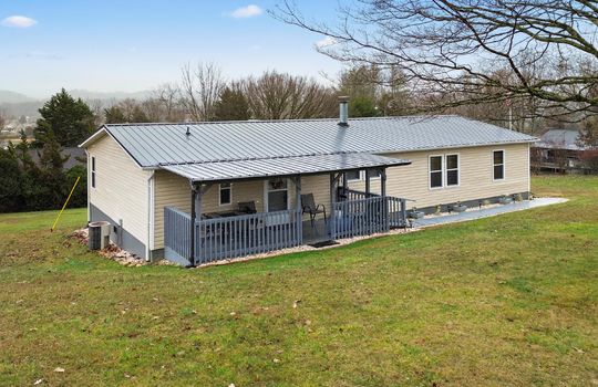 double wide, vinyl siding, covered front porch, metal roof, ramp access to porch, front yard, landscaping, trees, mountain views