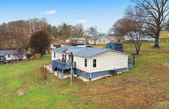 side view, side yard, storage shed, double wide, vinyl siding, back deck, covered front porch, carport, mountain views, neighboring homes