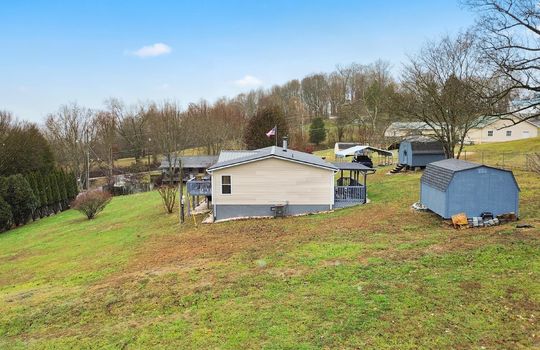 side view, side yard, storage shed, double wide, vinyl siding, back deck, covered front porch, carport, mountain views, neighboring homes