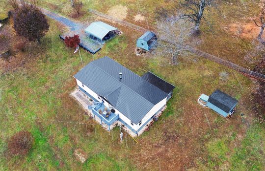 aerial photo, roof, metal roof, back deck, landscaping, covered front porch, storage sheds, carport, gravel driveway