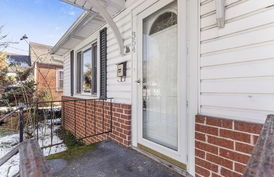 front door, storm door, covered front porch, vinyl siding, brick