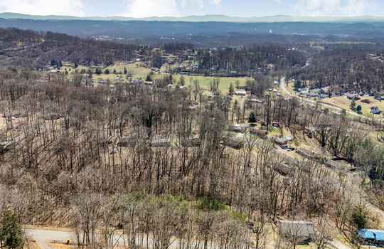 aerial view of land, neighboring properties, mountain views, road, pasture, fields