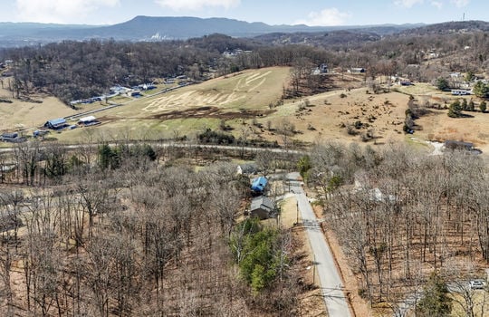 aerial view of land, neighboring properties, mountain views, road, pasture, fields
