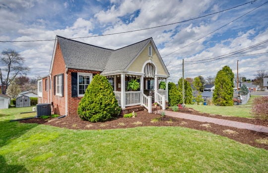 left side view of home, brick, traditional home, covered front porch, brick sidewalk, landscaping, front yard, side yard