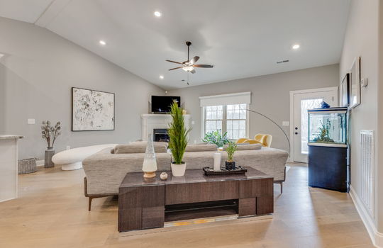 living room, luxury vinyl flooring, ceiling fan, recessed lighting, vaulted ceilings, windows, door