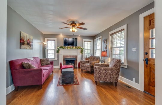 living room, hardwood flooring, windows, ceiling fan, fireplace, front door