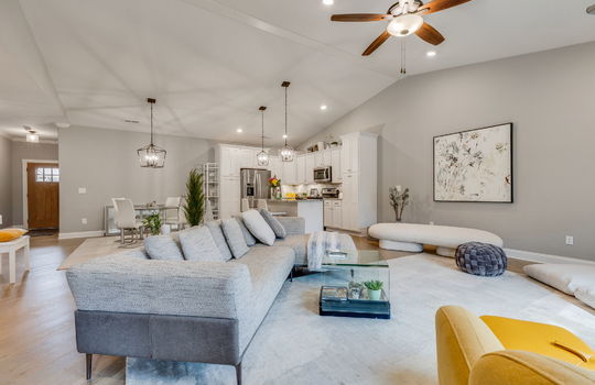 living room, vaulted ceiling, recessed lighting, ceiling fan, luxury vinyl flooring, kitchen dining space, front door