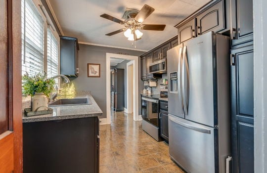 kitchen, stone counters, cabinets, stainless appliances, built in microwave, oven/range, refrigerator, tile flooring, ceiling fan, sink, window above sink