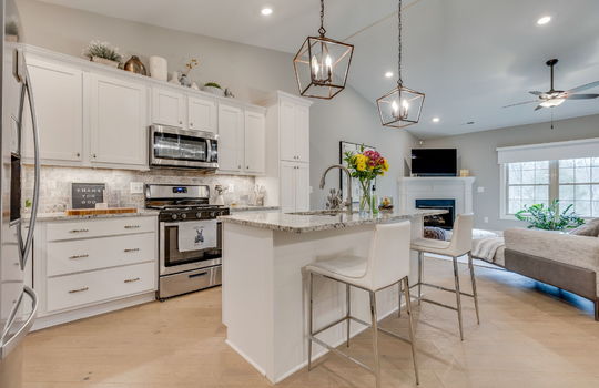 kitchen, kitchen island, granite countertops, refrigerator, oven/range, built in microwave, cabinets, luxury vinyl flooring,