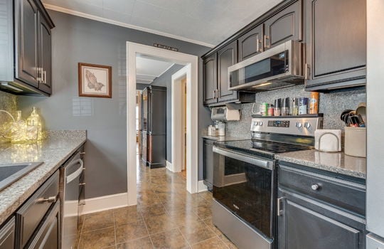 kitchen, tile flooring, stainless appliances, dishwasher, oven/range, built in microwave, stone counters, stone backsplash, cabinets, sink