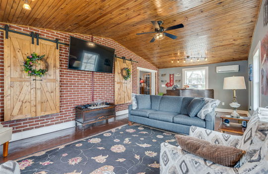 vaulted ceiling, bedroom/den, ceiling fan, light fixtures, concrete flooring, windows