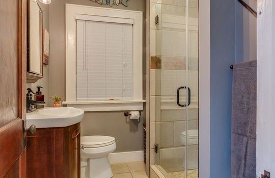 bathroom, shower, glass shower door, sink, toilet, tile flooring, window