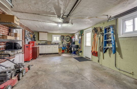 garage, concrete flooring, interior doorway, exterior doorway, windows, cabinets, storage shelves