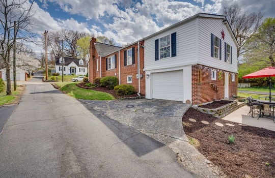 driveway, garage, garage door, rear patio, landscaping, traditional style home, brick, vinyl siding