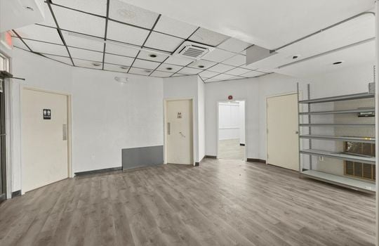 commercial property for lease, shelving, ceiling tiles, fluorescent lighting, bathroom entrance doors