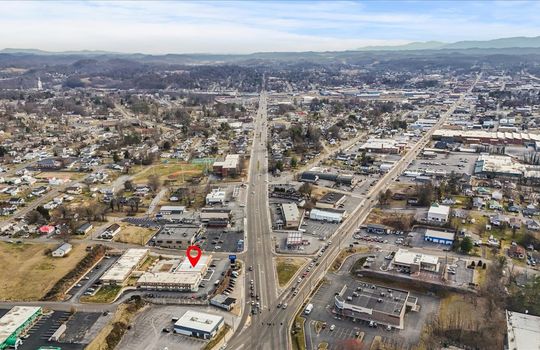 Aerial view of property with marker, roads, neighboring buinesses, mountain views