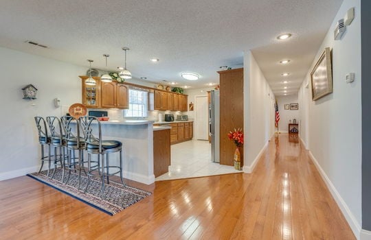 hallway, kitchen, bar seating, tile flooring, cabinets, recessed lighting, appliances