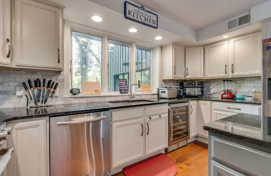 kitchen, wine refrigerator, sink, dishwasher, tile backsplash, cabinets, granite countertops, kitchen island, large windows above sink