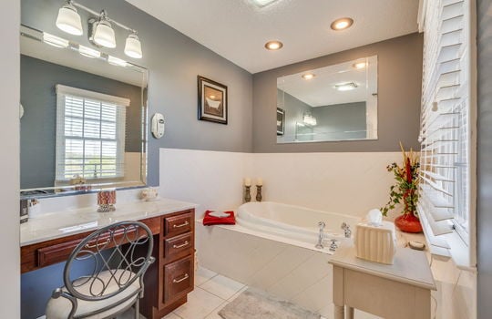 ensuite bathroom, bathtub, vanity, recessed lighting, tile flooring, window