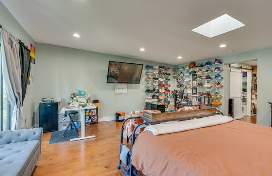 primary bedroom, skylight, recessed lighting, hardwood flooring, glass doors to balcony, walk in closet