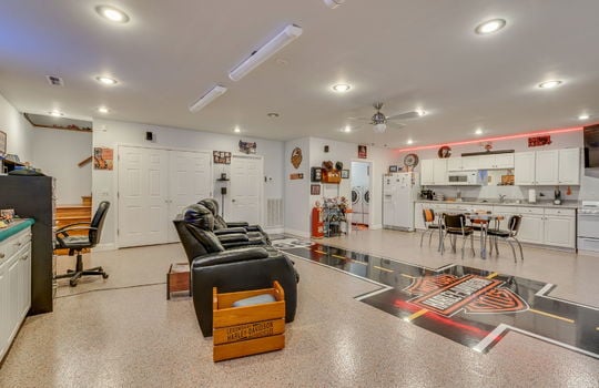 lower level living area, concrete flooring, custom flooring, kitchen, cabinets, countertops, sink, refrigerator, built in microwave, oven/range, recessed lighting, storage closets, bathroom, stairs to main level