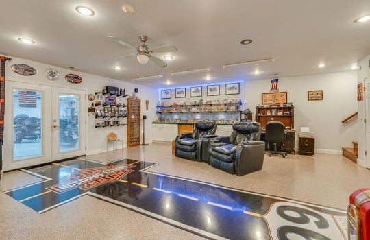 lower level living space, concrete flooring, custom painted flooring, recessed lighting, ceiling fan, doors to garage, stairs to main level