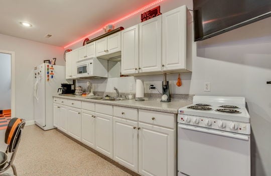 lower level kitchen, oven/range, cabinet,s countertops, built in microwave, sink, refrigerator