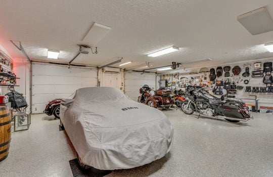 two car drive under garage, concrete flooring, fluorescent lighting, storage shelving, garage doors, exterior door
