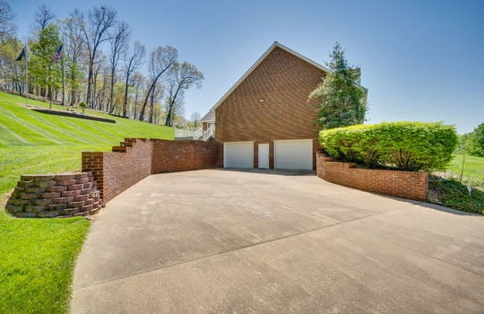 driveway, two car drive under garage, exterior entry door, retaining walls, brick home exterior, back yard, landscaping
