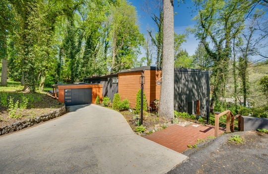 driveway, garage door on carport, brick stairs, mature trees, landscaping