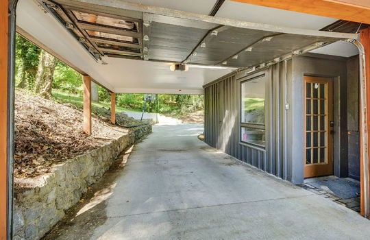 carport, interior entry door, concrete pad, rock retaining wall, driveway