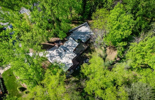 aerial view of home, back yard, roof, driveway, parking, trees