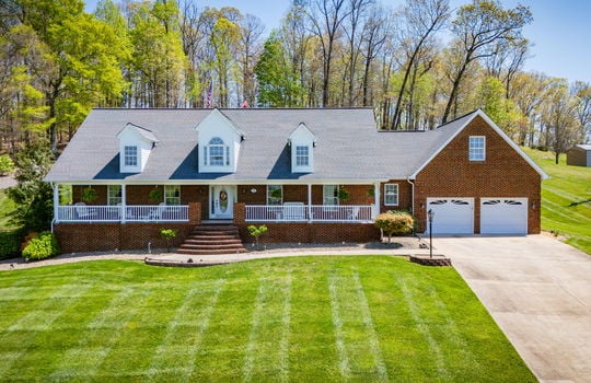 brick, two story home, covered front porch, brick porch steps, landscaping, two car garage, driveway, trees