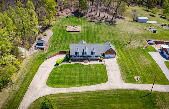 aerial view of property, driveways, front yard, back yard, trees, neighboring properties, front porch, two car garage, brick exterior