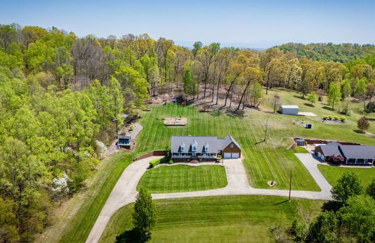Aerial view of property, front yard, driveway, two car garage, front porch, back yard, trees, neighboring homes