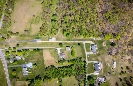 aerial view of home, neighboring properties, trees, road, driveway