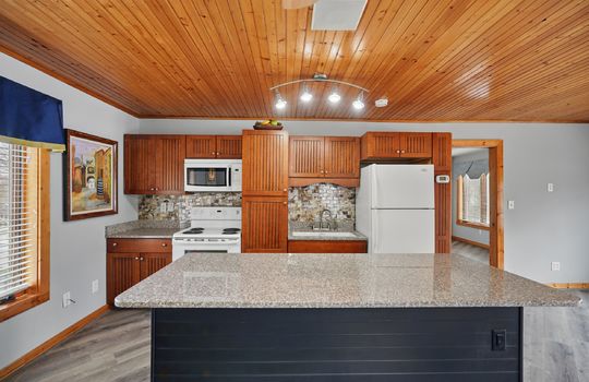 kitchen, kitchen island, kitchen sink, cabinets, countertops, microwave, oven/range, refrigerator, wood ceiling, luxury vinyl flooring