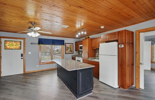 kitchen, exterior door, kitchen island, cabinets, countertops, sink, refrigerator, oven/range, microwave, luxury vinyl flooring, wood ceiling