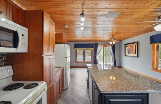 Kitchen, oven/range, microwave, refrigerator, sink, cabinets, countertops, wood ceiling, ceiling fans, door to balcony, windows, luxury vinyl flooring