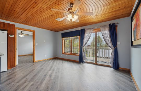 luxury vinyl flooring, living space, open to kitchen, door to balcony, wood ceiling, wood trim, windows