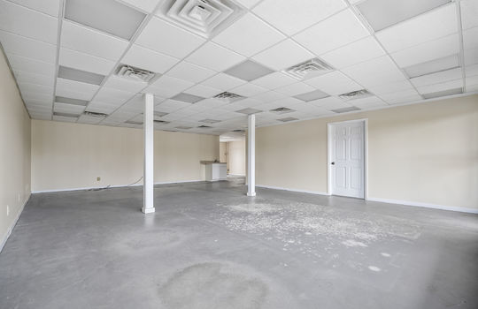 open space, pillars, concrete flooring, door, ceiling tiles, fluorescent lighting