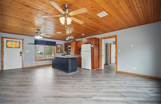 exterior door, kitchen island, ceiling fans, cabinets, countertops, wood ceiling, microwave, oven/range/refrigerator, luxury vinyl flooring, living space