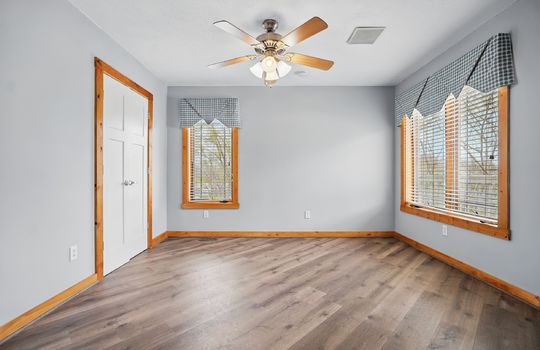bedroom, luxury vinyl flooring, wood trim, ceiling fan, closet, windows