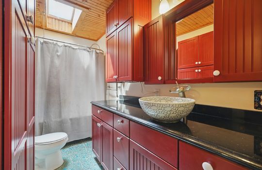 bathroom, storage cabinets, shower/tub, toilet, sink, wood ceiling, skylight