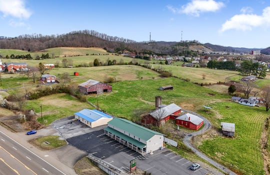 aerial view of property, parking lot, commercial building, commercial space for lease, parking lot, road, nearby homes, farms, fields, mountain views
