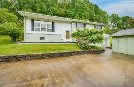 split level h9ome, yard, retaining wall, driveway, shed, brick, wood siding, front door, trees, landscaping
