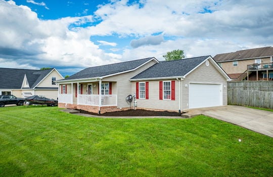 right side view of home, ranch style home, driveway, garage door, vinyl siding, covered front porch, front door