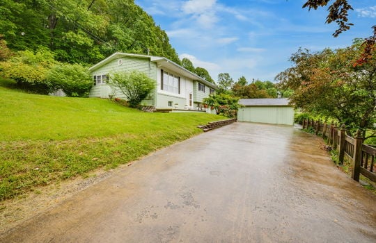 driveway, yard, brick & wood siding exterior, front door, shed/workshop, trees, landscaping, fencing