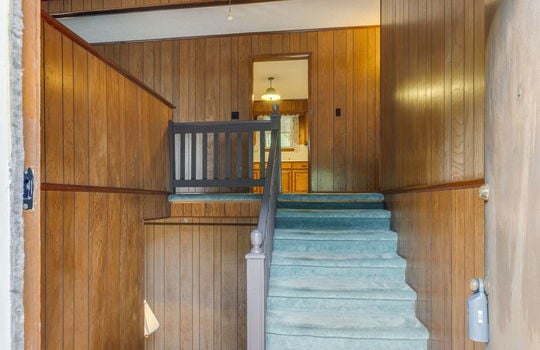 split level entry, carpeted stairs, paneling walls, ceiling fan, wood landing