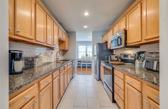 kitchen, countertops, cabinets, refrigerator, stove, built-in microwave, sink, dishwasher, tile backsplash, tile flooring, recessed lighting